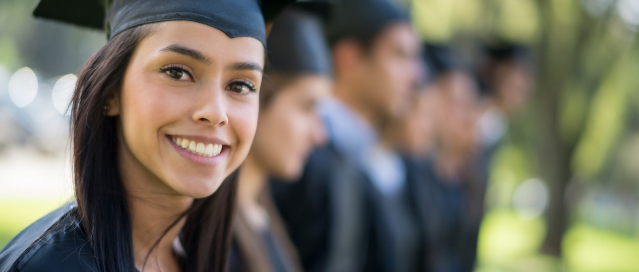 Female high school senior in graduation cap and gown smiling and looking at camera